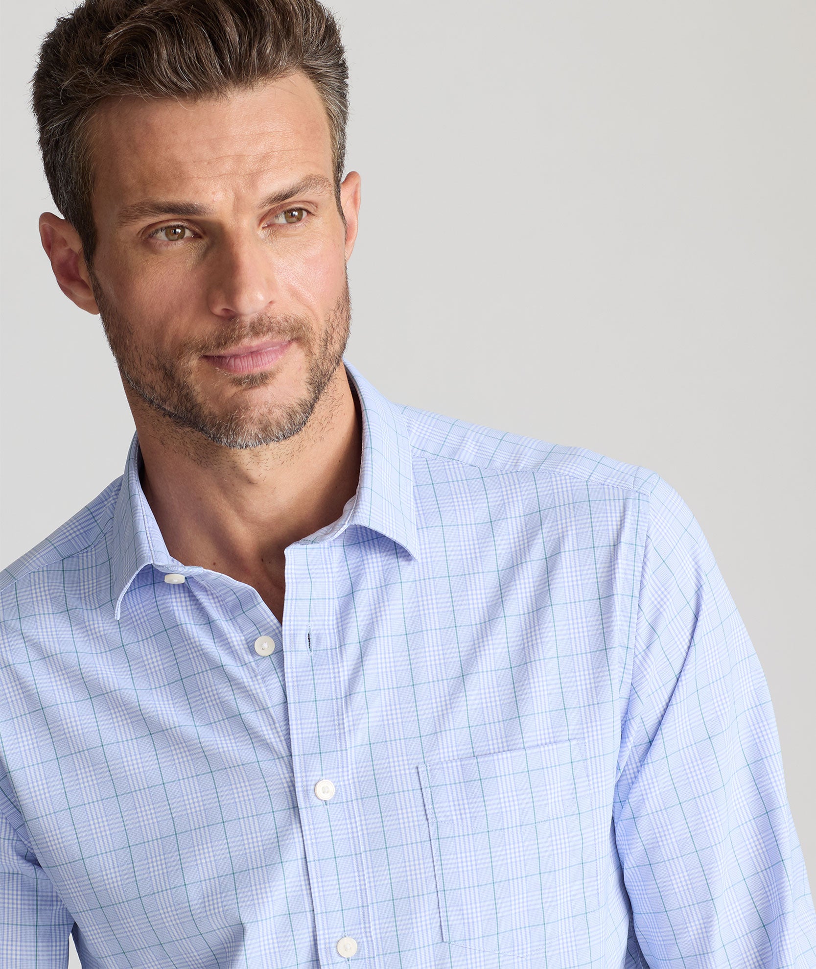 Model is wearing UNTUCKit Mason performance shirt in light blue check. 