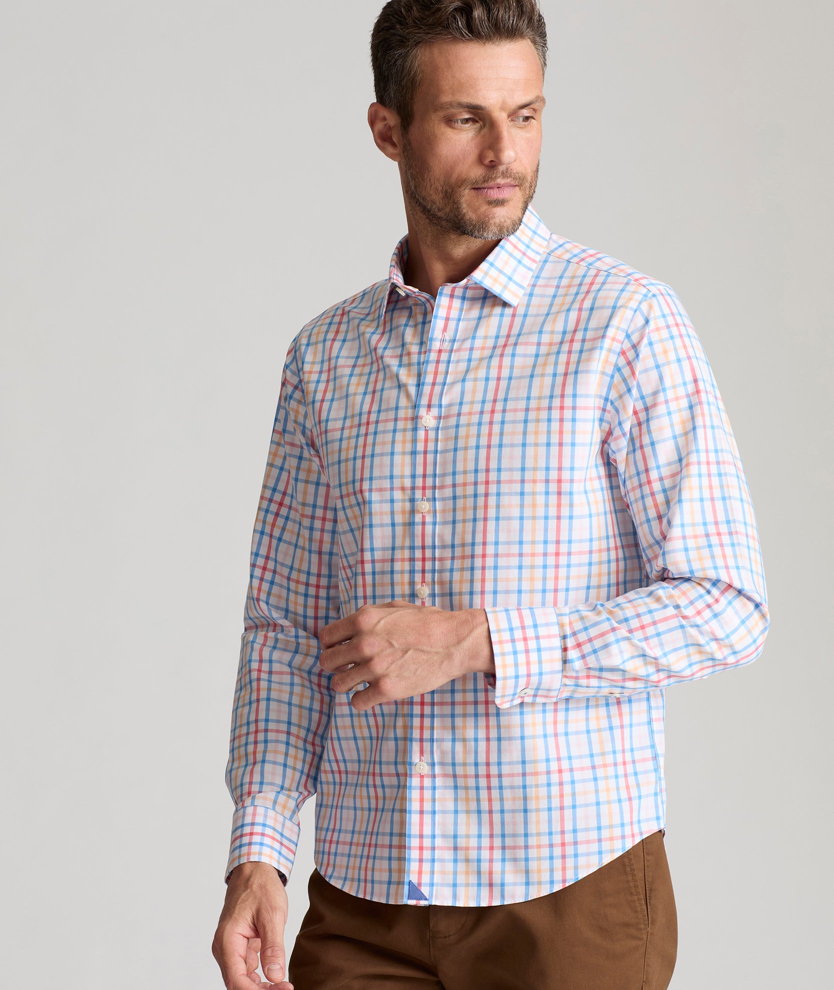 Model is wearing UNTUCKit Moore shirt in blue, orange and pink check.