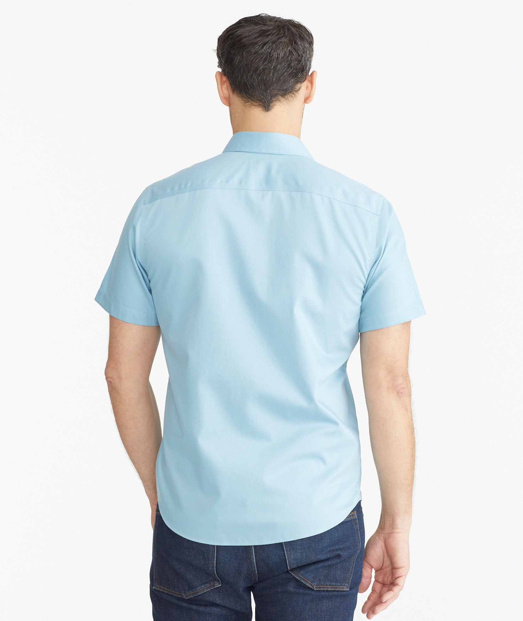 Model is wearing UNTUCKit Light Blue Denim Wrinkle-Free Short-Sleeve Hargrove Shirt.